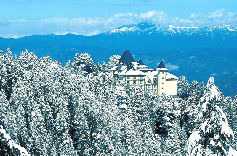 a building on top of a snow covered mountain at Wildflower Hall, An Oberoi Resort, Shimla in Shimla